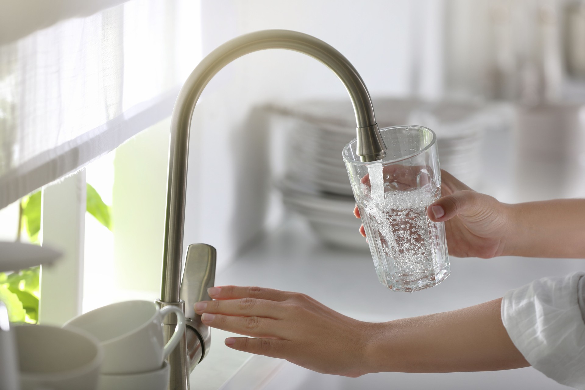 Frau gießt Wasser in Glas in Küche, Nahaufnahme